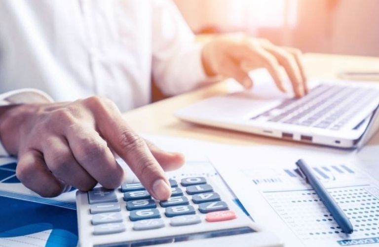 A man working on a calculator and a laptop