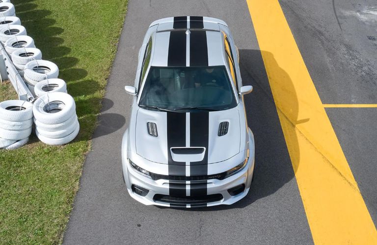 A white color 2022 Dodge Charger is running on the road with tires kept nearby
