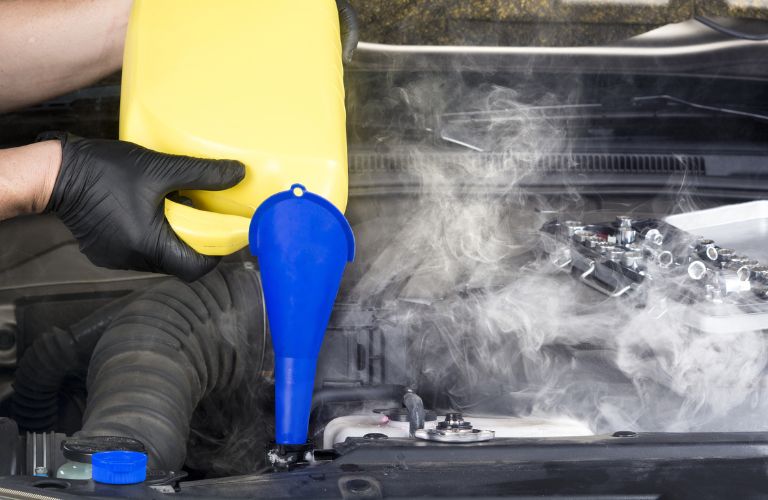 An image of a mechanic filling up the coolant of the vehicle.